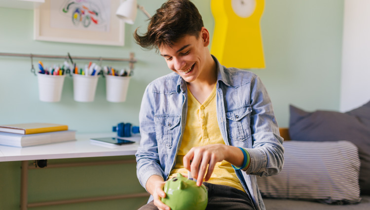 Teen putting money into a piggy bank to save.